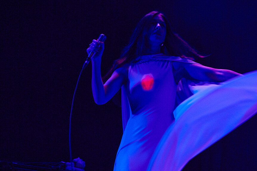 Weyes Blood wears a light-up chest-piece that mirrors the thrift shop Jesus chic of her ...Hearts Aglow album artwork.
