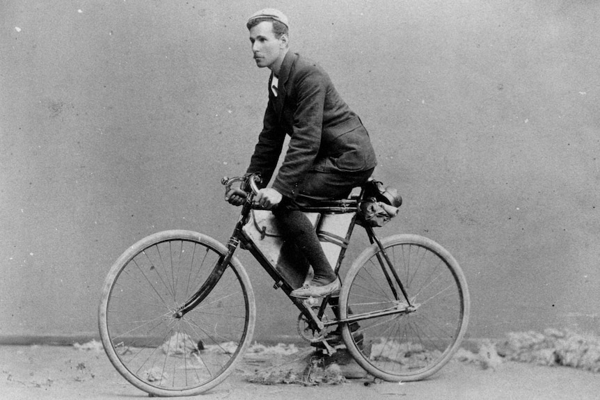 An historical photo of a man on a bicycle.