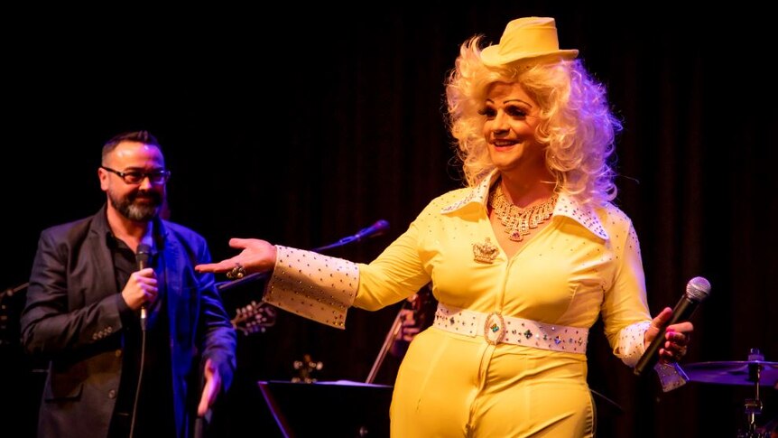 Dolly Diamond dressed in a yellow outfit on stage