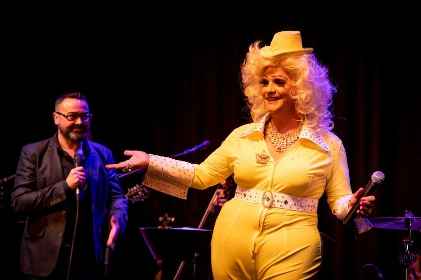 Dolly Diamond dressed in a yellow outfit on stage