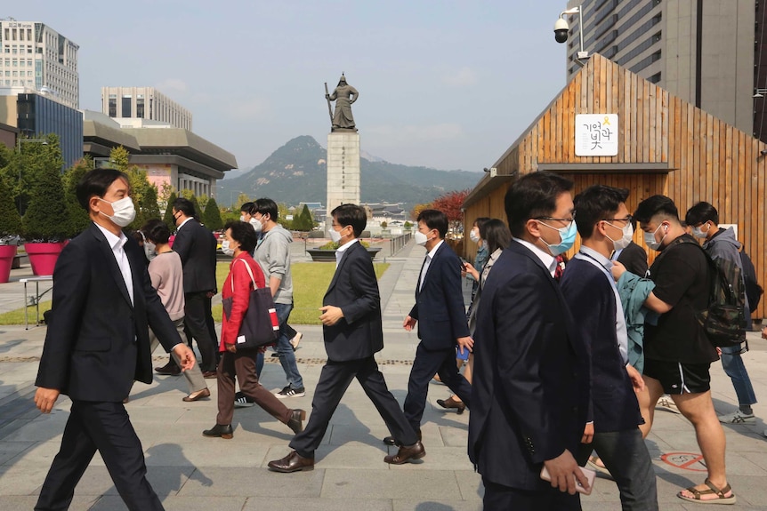 People cross the street in Seoul wearing masks