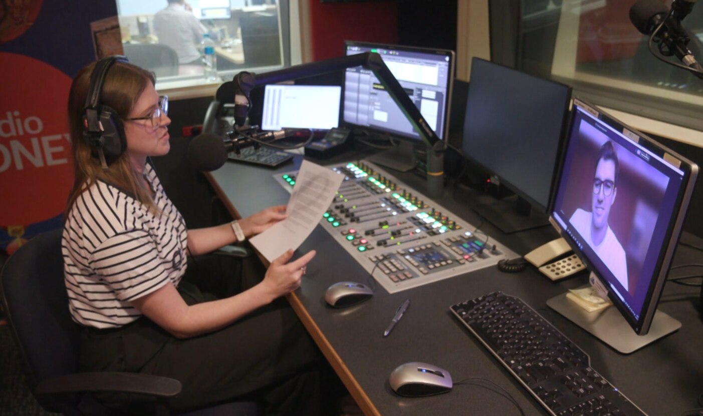 A woman with shoulder length brown hair in a radio studio presenting a podcast.