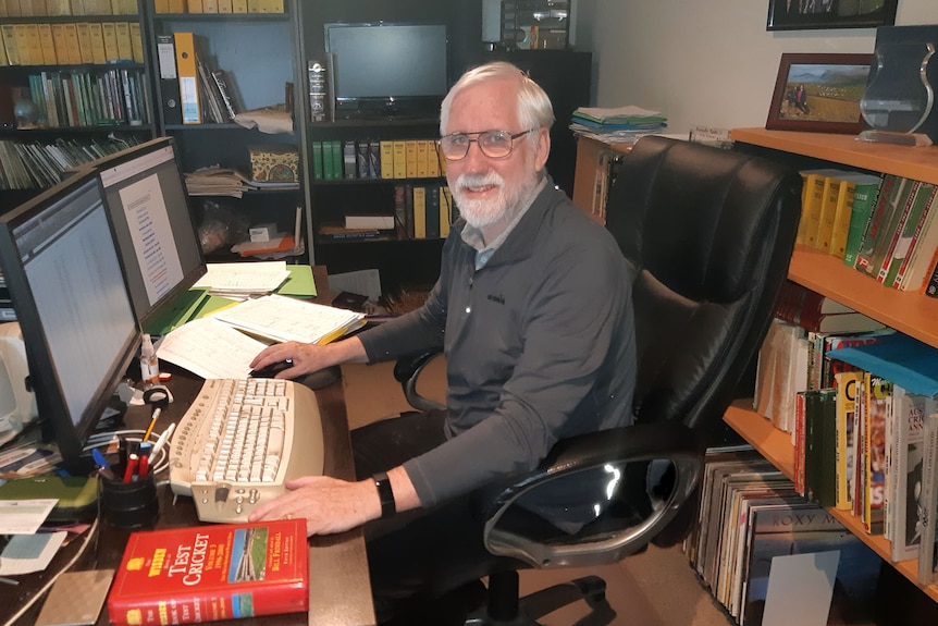 A man sits at a desk in his office.