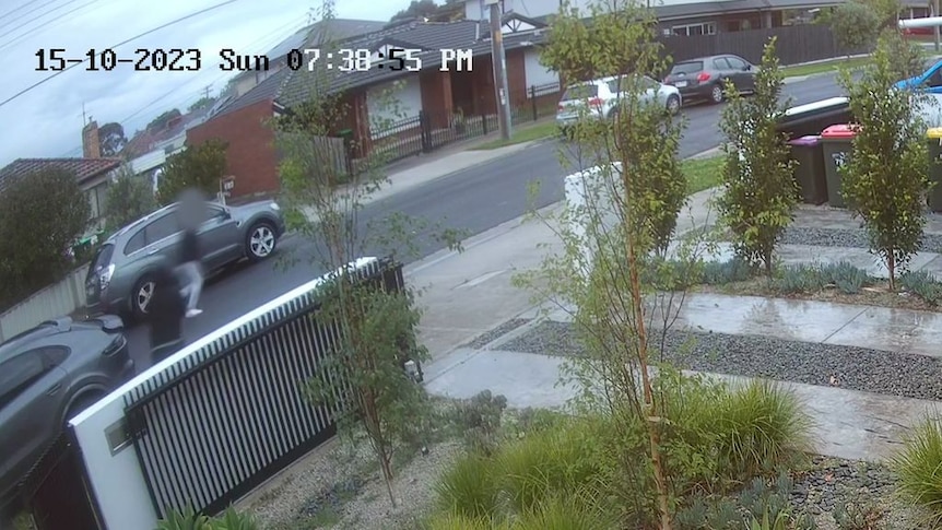 A still frame from CCTV showing a suburban yard, street, and two men running.