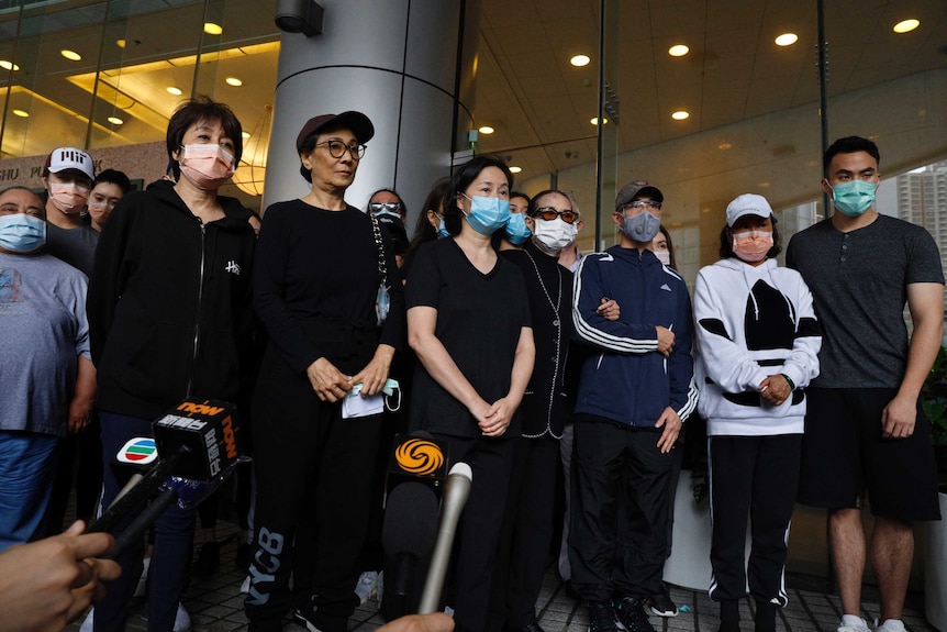 Family members of Macau tycoon Stanley Ho stand outside a hospital wearing face masks.