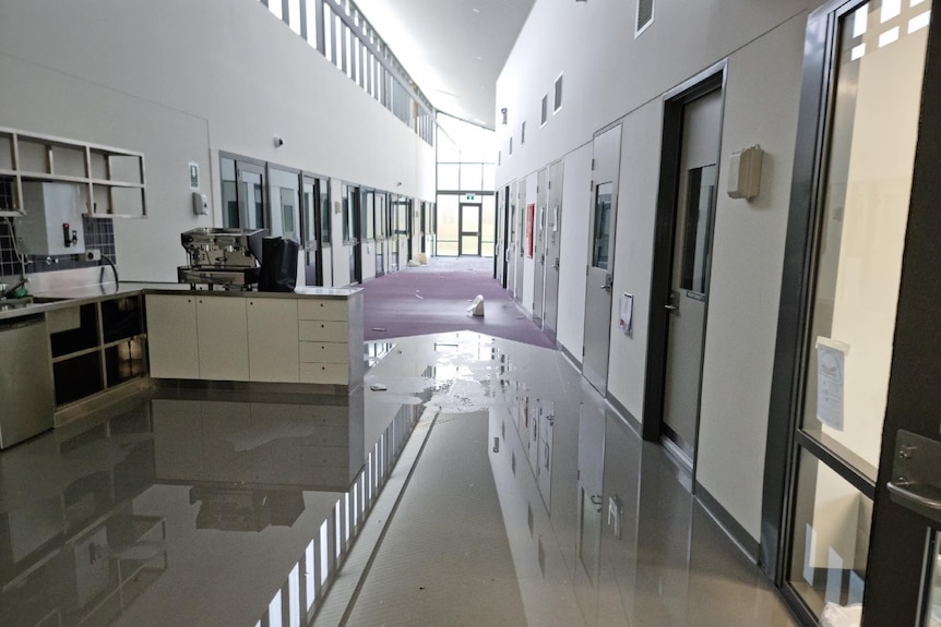 A prison hallway is covered by water and debris.