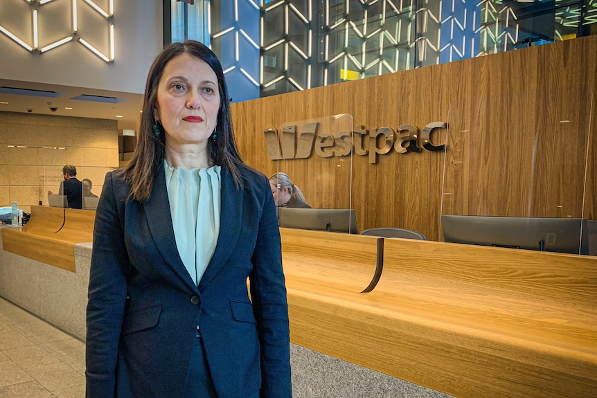 Woman in suit stands in front of Westpac corporate signage