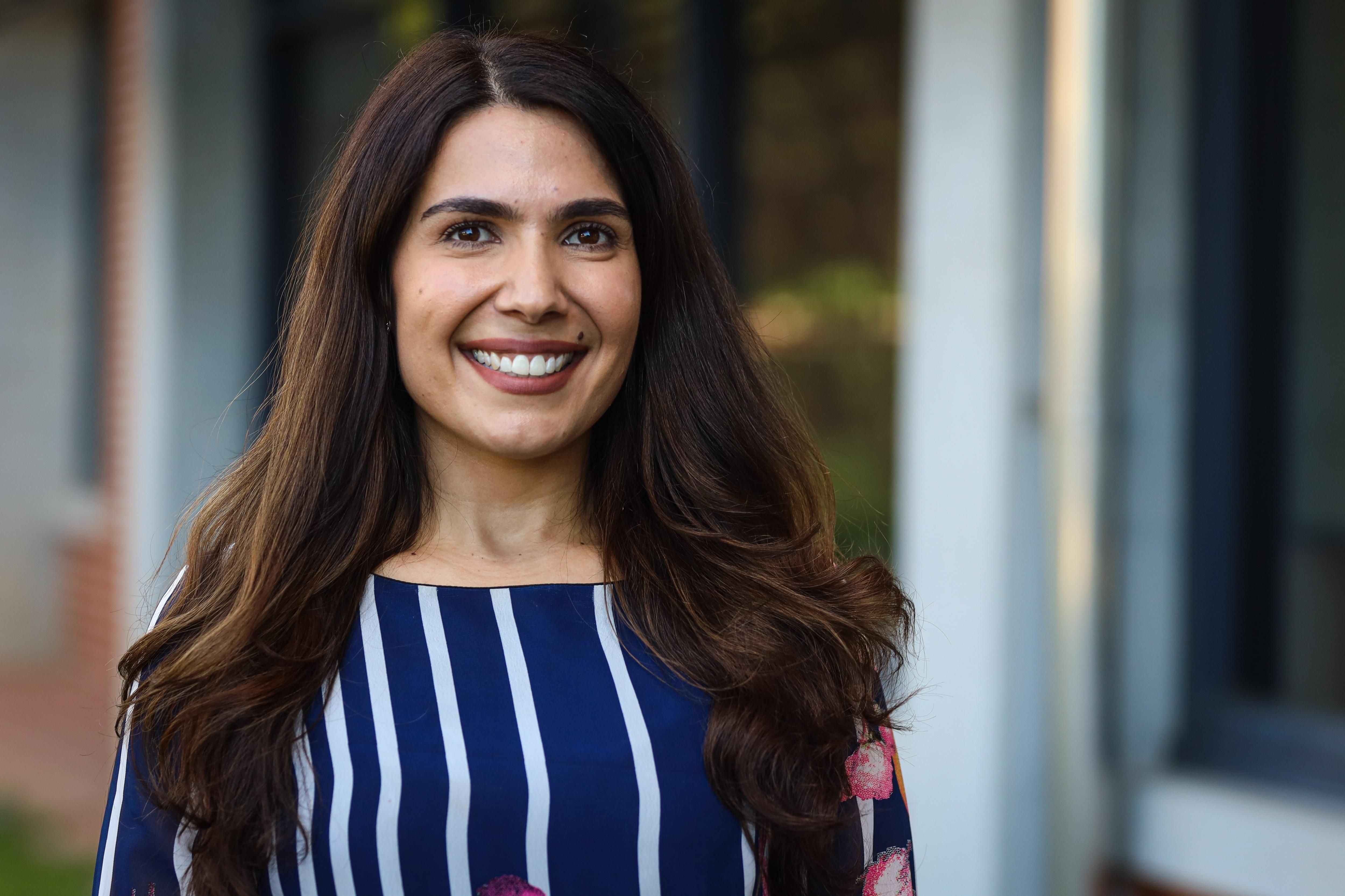 A smiling woman poses in front of the camera. 