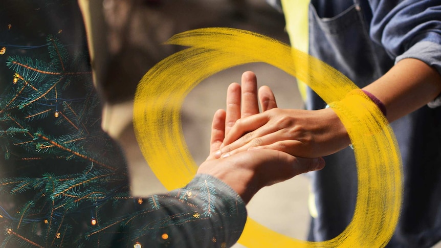 Two people holding hands with a yellow brush stroke around their hands to depict how to help lonely people over Christmas.