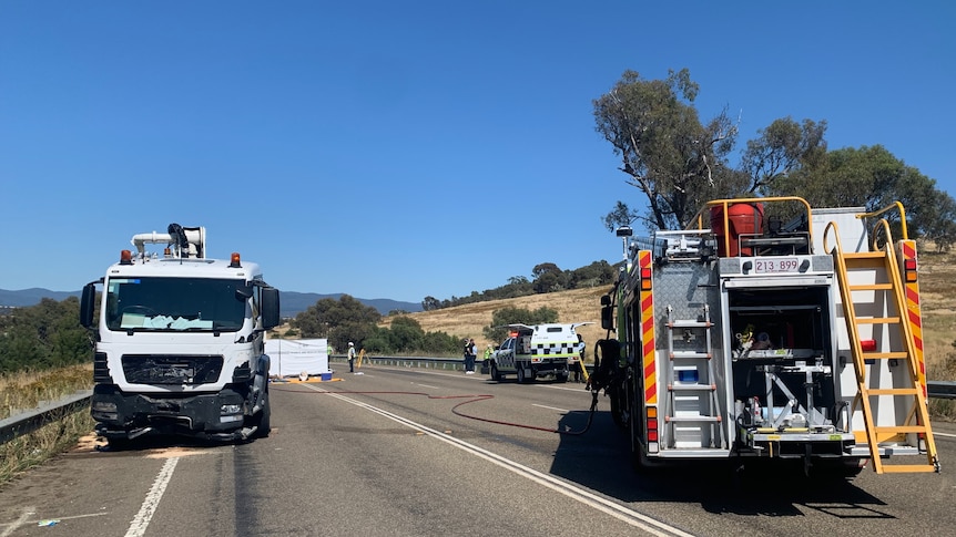 A large truck post crash on a highway next to a firetruck responding to the scene.