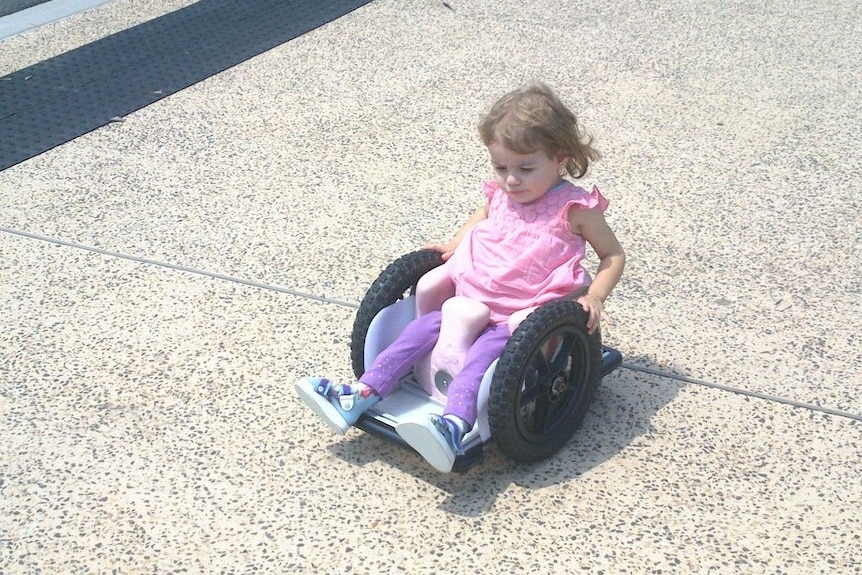Brydi Saul as a young girl, sitting in a makeshift wheelchair.