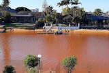 Photo of a Gold Coast canal with red stained water.