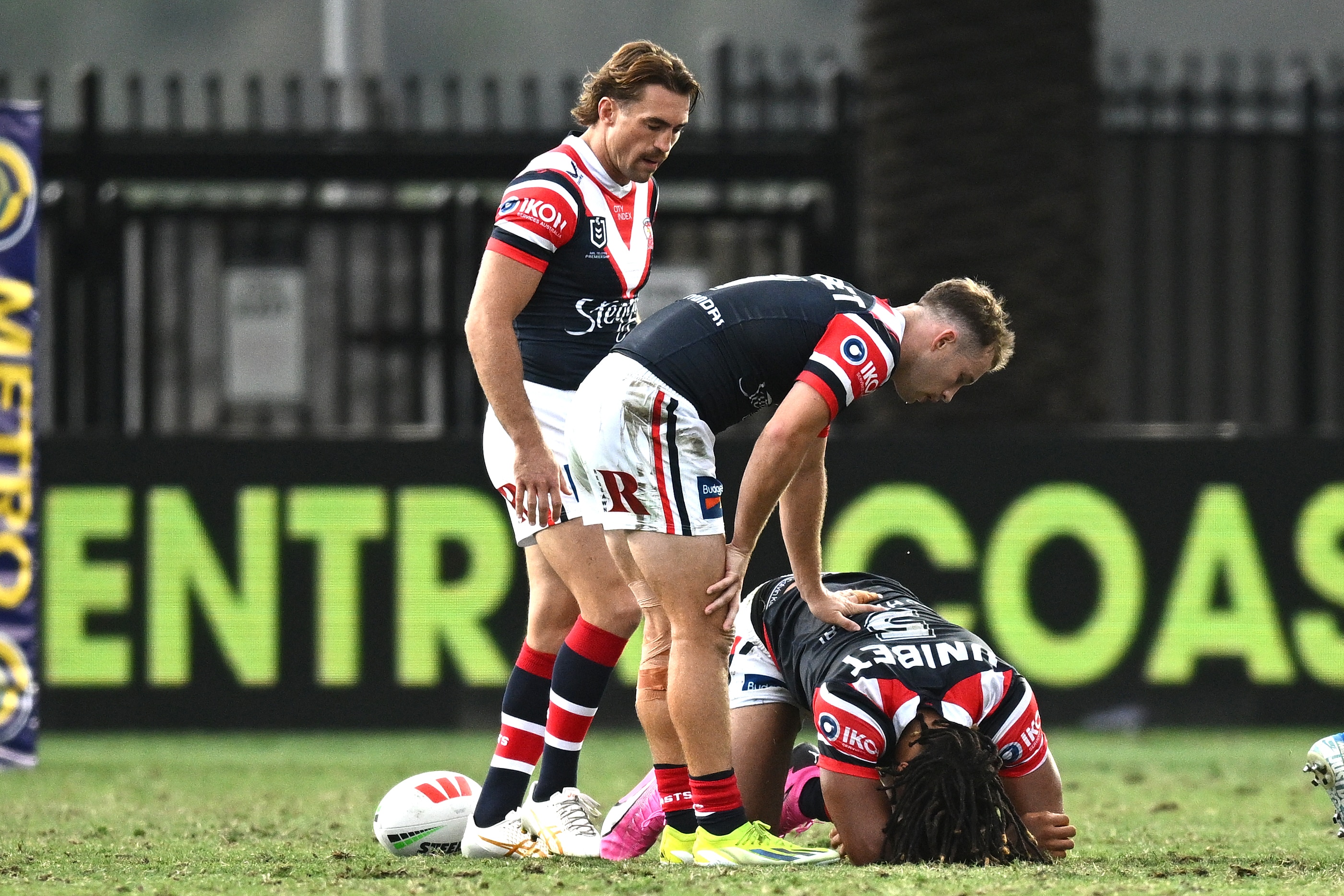 Dom Young is on his haunches on the ground as teammates attend to him