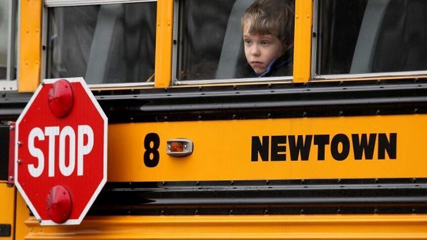 A child gazes from a school bus as it passes by the mourners at a funeral in Newtown.