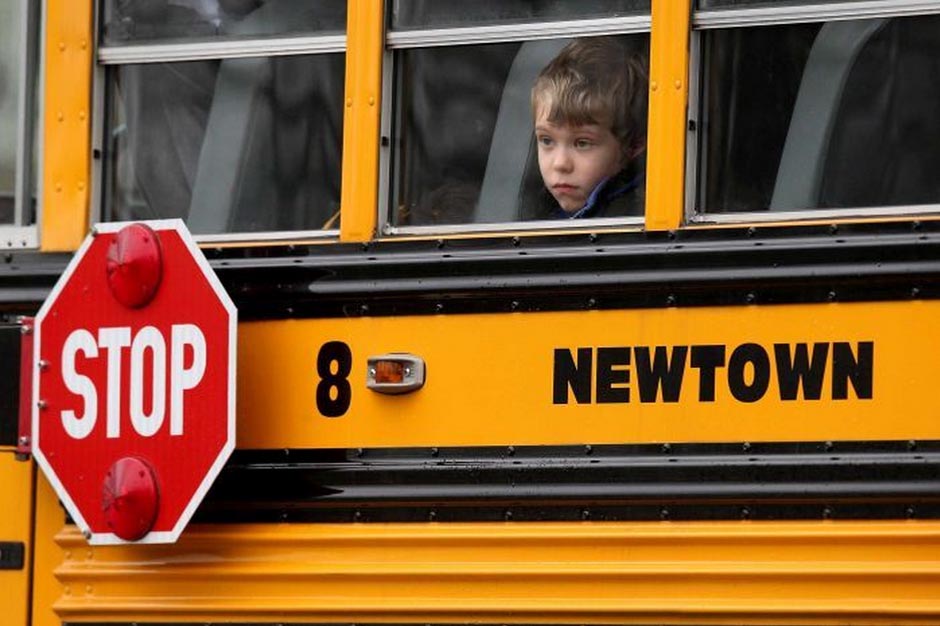 A child gazes from a school bus as it passes by the mourners at a funeral in Newtown.