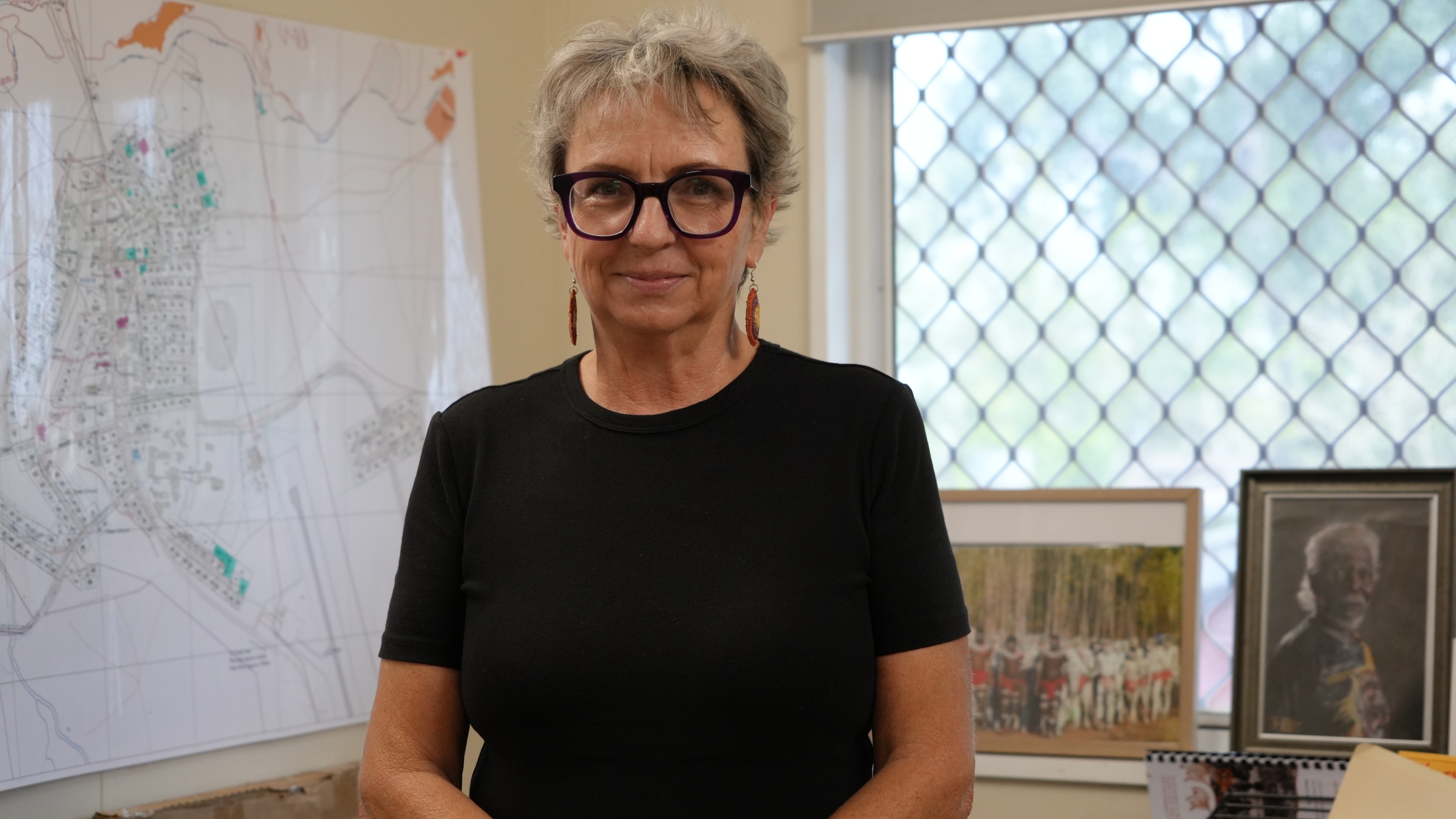A woman with short hair wearing a black shirt standing in an office.