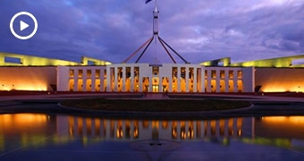 A wide-angle shot of Australia's Parliament House with a cloudy, night sky above it.