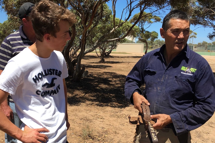 Man talks to farmer about how to set a wild dog trap.