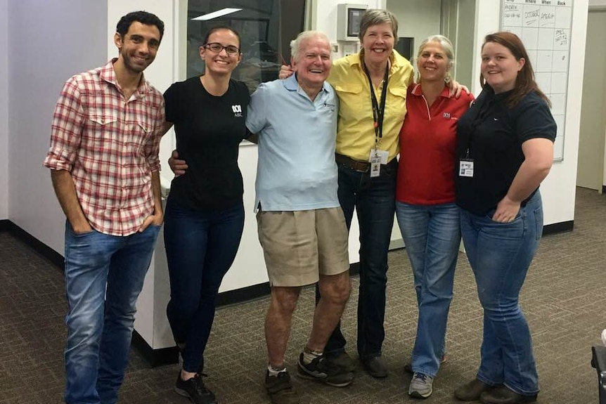 Group of people stand with arms around each other