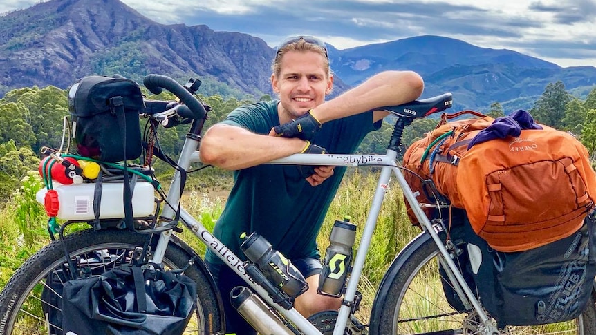 A smiling young man with his touring bike