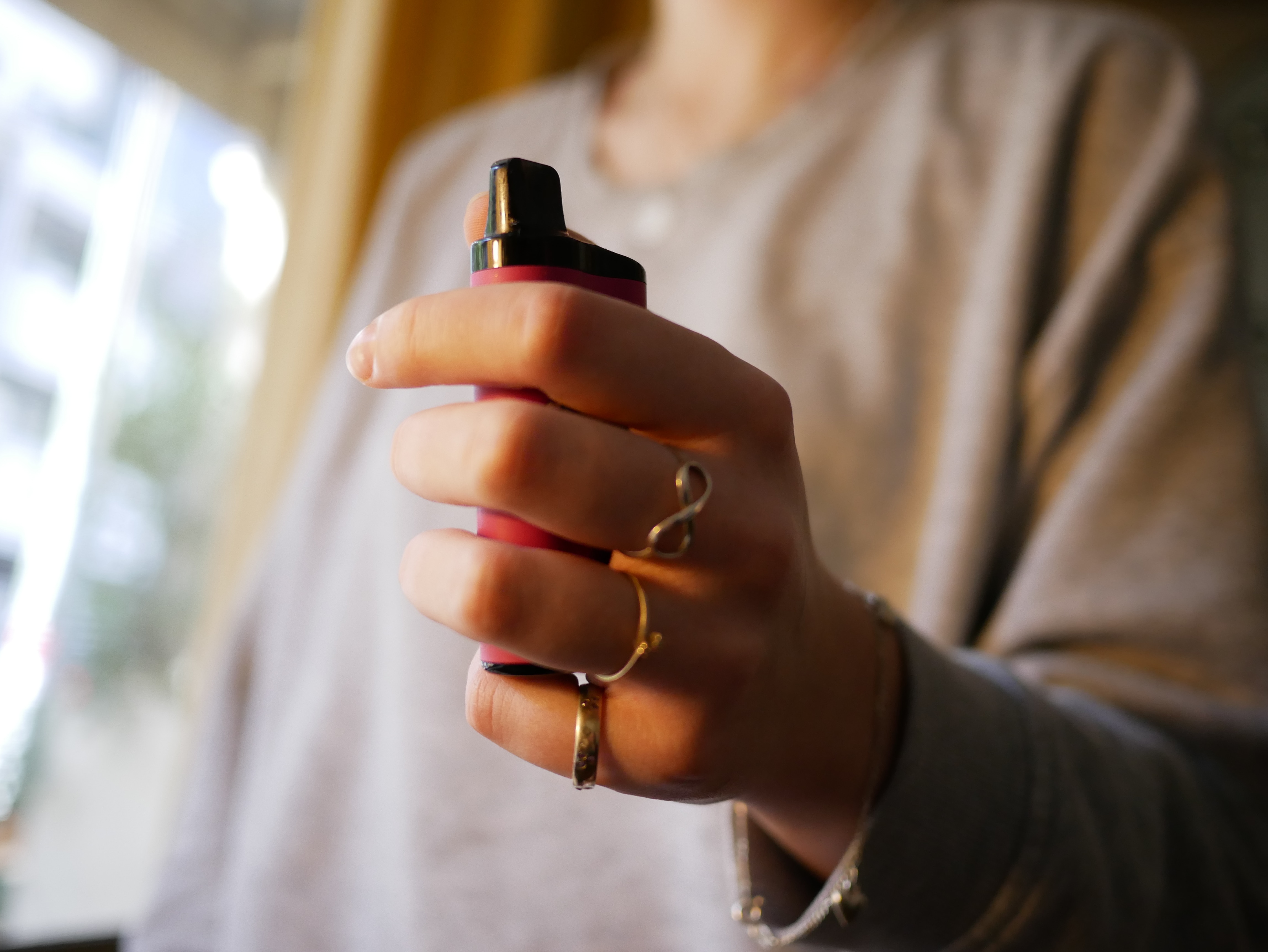 An image of a teenager's hand holding a vape.