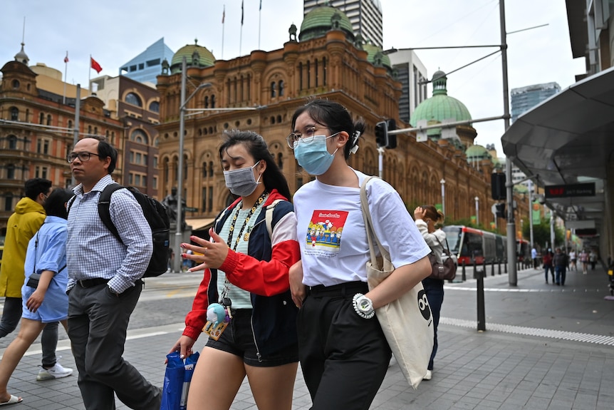 young women wearing masks walking on the street