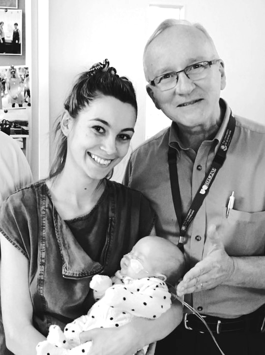 Mum holding her baby with an older man who is a doctor.