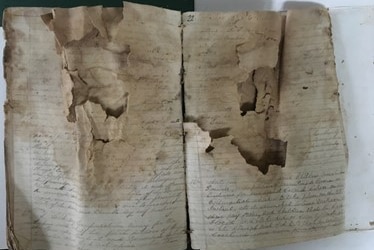 Photograph of an old book that is handwritten and in a severe state of disrepair