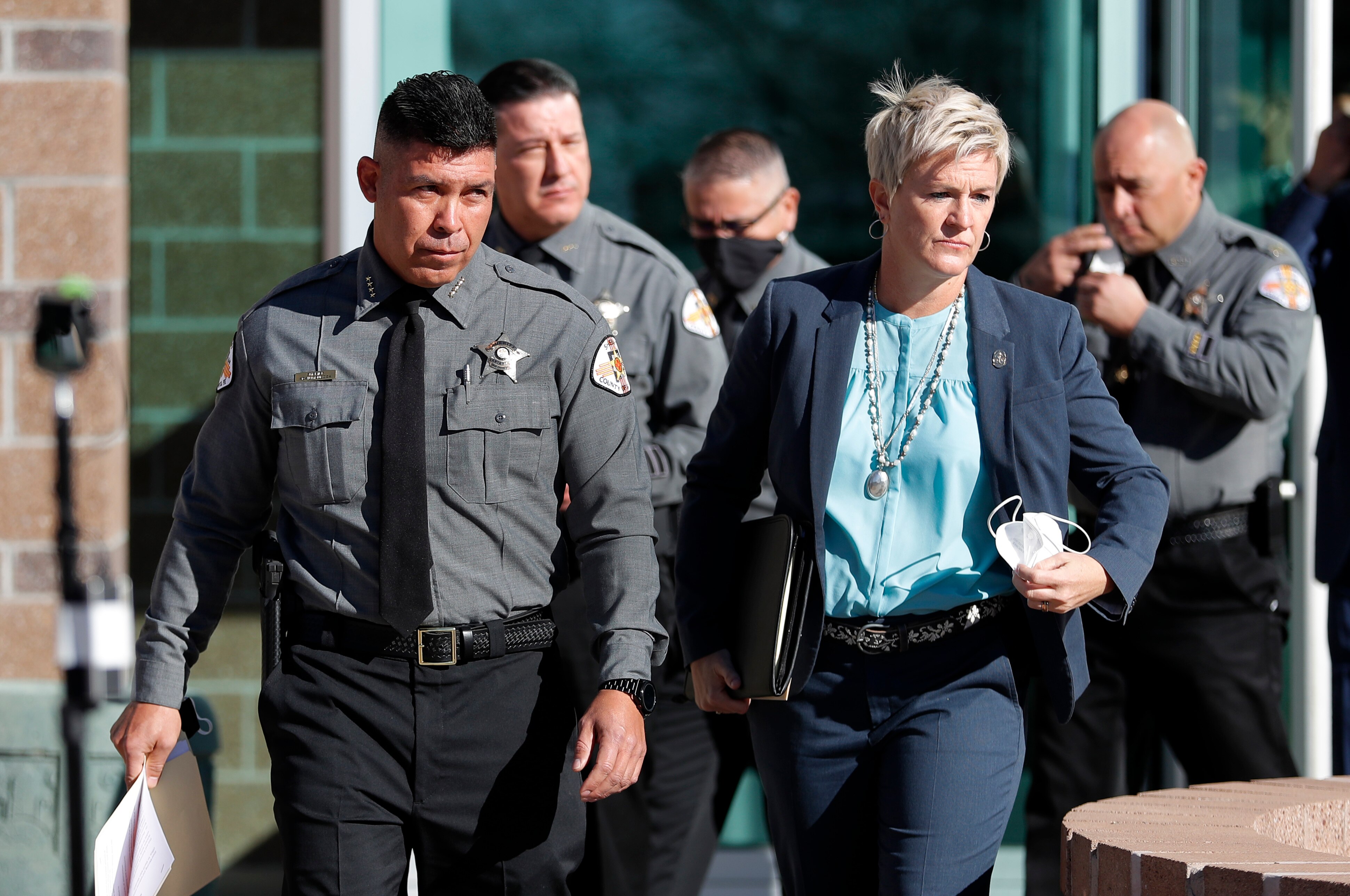 A police man in uniform and a lawyer with short blond hair walk