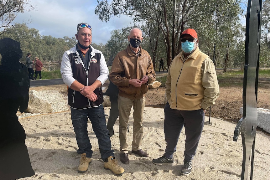 three men standing next to each other