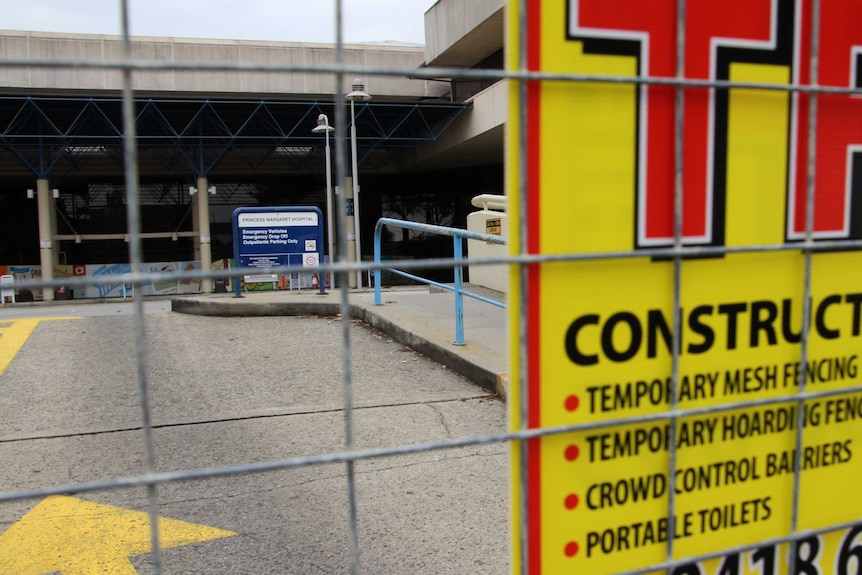 A fenced off emergency vehicle ramp outside Princess Margaret Hospital with a construction sign on the fence.