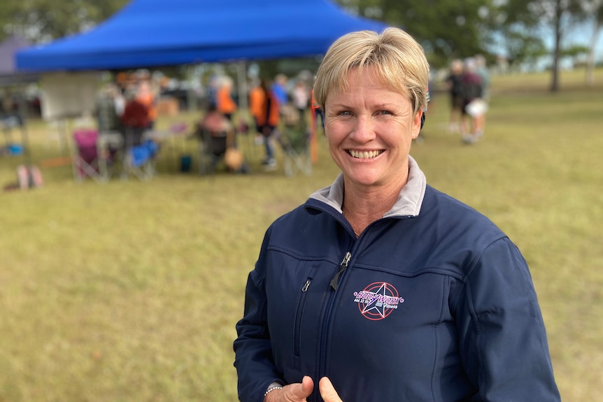 A woman with short blonde hair and wearing a blue jacket smiles at the camera.