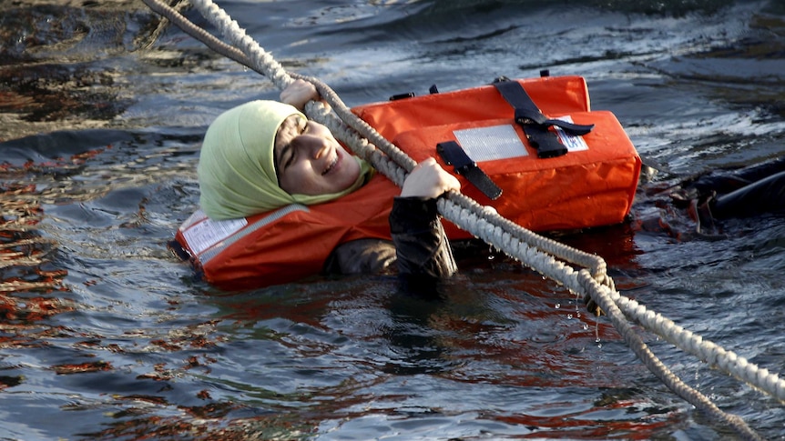 A woman stuck at sea desperately hangs onto a rope.
