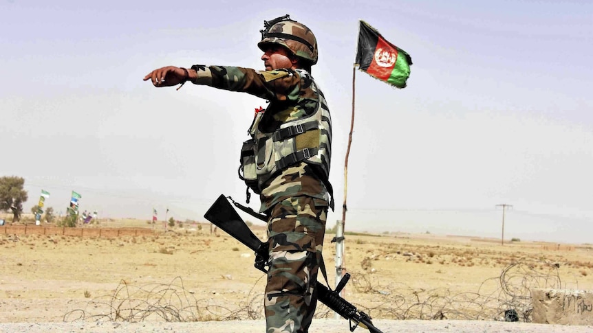 An Afghan soldier directs a vehicle to stop at a checkpoint.