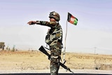 An Afghan soldier directs a vehicle to stop at a checkpoint.