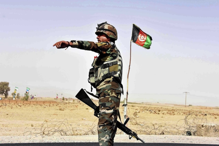 An Afghan soldier directs a vehicle to stop at a checkpoint.