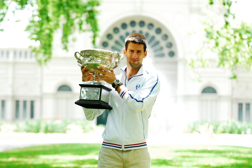 Novak Djokovic poses for photos with the trophy the day after winning the Australian Open.