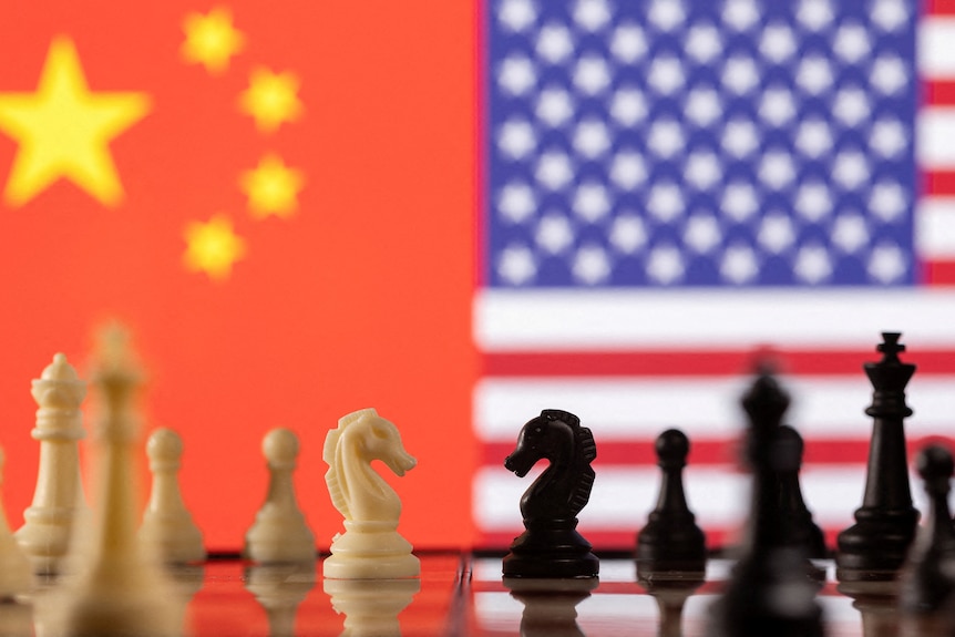 Chess pieces are seen in front of displayed China's and U.S. flags.