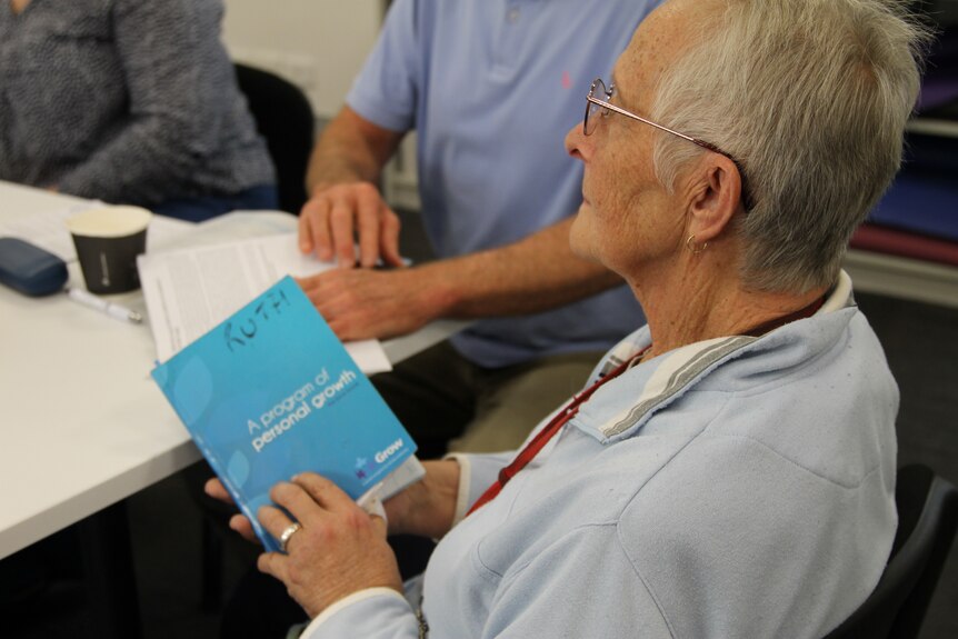 woman at meeting holds blue book