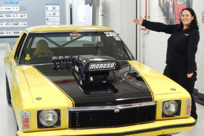 A woman points to a Holden ute.