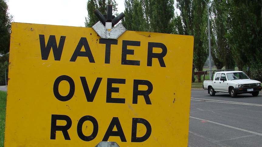 Water over road warning sign during flood