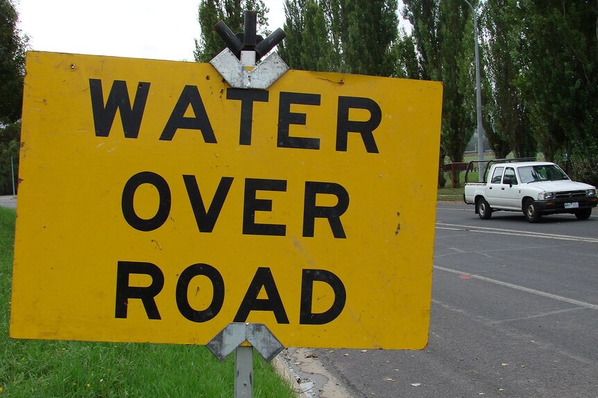 Water over road warning sign during flood