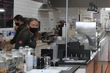 The inside of a diner with a waitress smiling at the camera with a mask on.