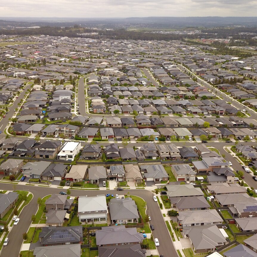 An aerial view of hundreds of houses spread across green lands