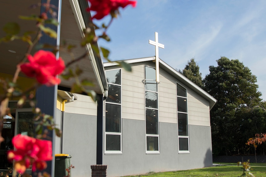 Exterior of a contemporary Catholic Church, with out of focus roses in the foreground