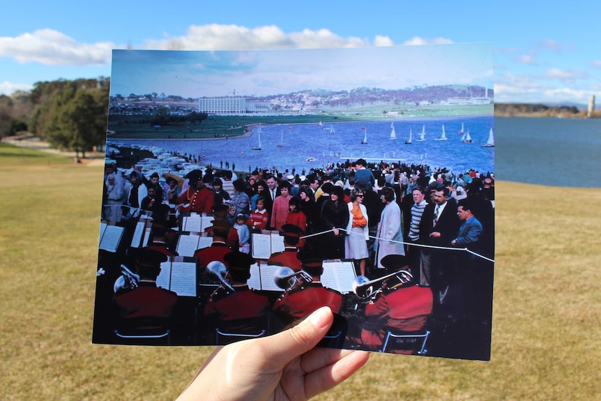 A hand holding a historic photo of Regatta Point with how it looks today in the background.
