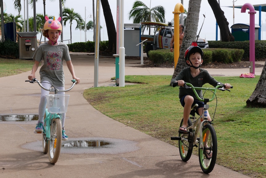 Two children riding bikes on an esplanade.