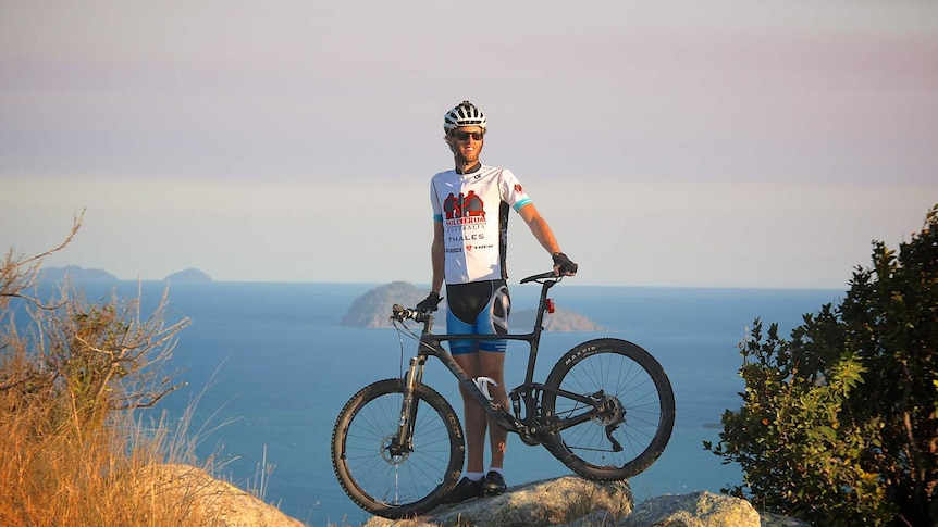 Mackay pilot Ash Hogan stands on a mountain with his bicycle ahead of his fundraising attempt for Papua New Guinea charities