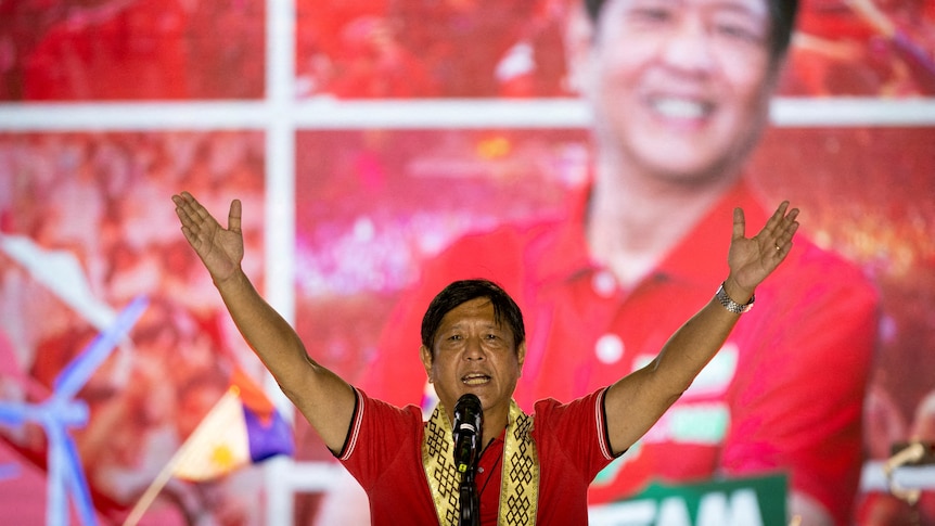 A man holds his hands aloft while campaigning.