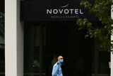 A masked security guard stands outside the entrance of the Novotel hotel, on Murray Street in Perth.